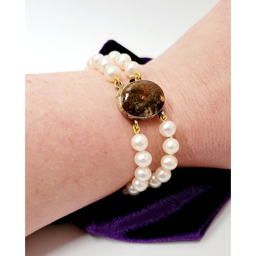 16 - A BEAUTIFUL DOUBLE ROW PEARL BRACELET WITH GEORGIAN GOLD CLAPS which holds a stone within it. The cl... 