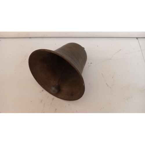 186 - AN ANTIQUE BRONZE BELL, 13cm tall x 11cm wide. In working order.