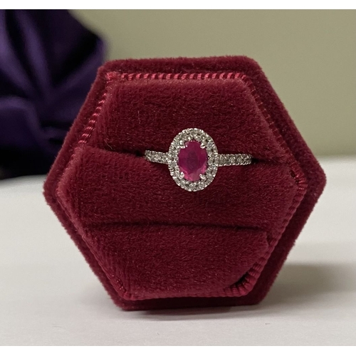 20 - A BEAUTIFUL 18CT WHITE GOLD RUBY AND DIAMOND HALO CLUSTER RING, with central oval cut ruby in four c... 