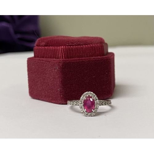 20 - A BEAUTIFUL 18CT WHITE GOLD RUBY AND DIAMOND HALO CLUSTER RING, with central oval cut ruby in four c... 