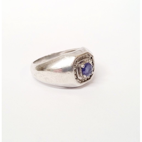 228 - A GENTLEMANS STERLING SILVER RING, with a centrally placed blue stone, surrounded by small clear gem... 