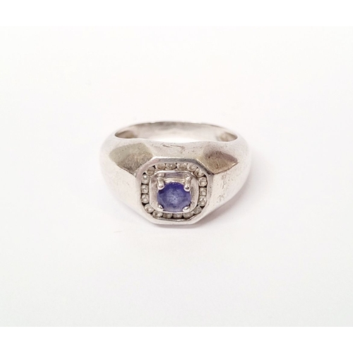 228 - A GENTLEMANS STERLING SILVER RING, with a centrally placed blue stone, surrounded by small clear gem... 