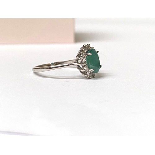 48 - A FANTASTIC 14CT WHITE GOLD EMERALD AND DIAMOND CLUSTER RING, with central oval cut emerald in four ... 