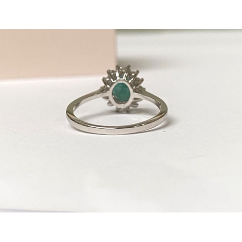 48 - A FANTASTIC 14CT WHITE GOLD EMERALD AND DIAMOND CLUSTER RING, with central oval cut emerald in four ... 