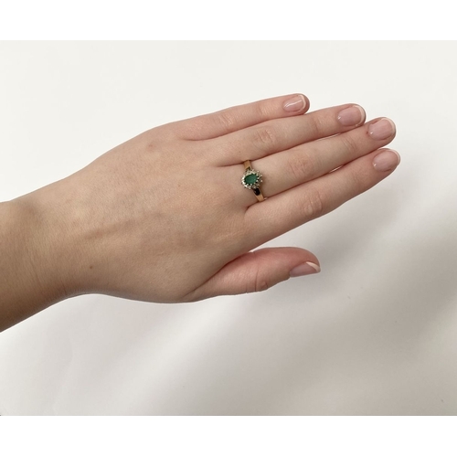 75 - A LOVELY 10CT YELLOW GOLD EMERALD AND DIAMOND CLUTSER RING, with central oval cut emerald in claw se... 