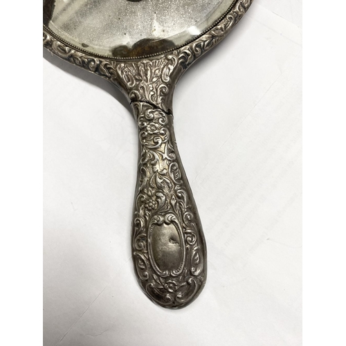 82 - A DECORATIVE SILVER HAND MIRROR, by Henry Matthews, Birmingham c.1929. The bevelled mirror with high... 