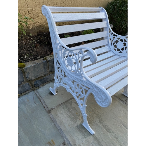 38 - A PAINTED CAST IRON GARDEN SEAT, with decorative scroll supports, slat back and seat. Dimensions: 60... 