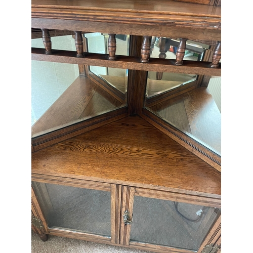 318 - AN OAK MIRROR BACKED CORNER CABINET, to the top is a raised gallery back with turned columns & a fin... 