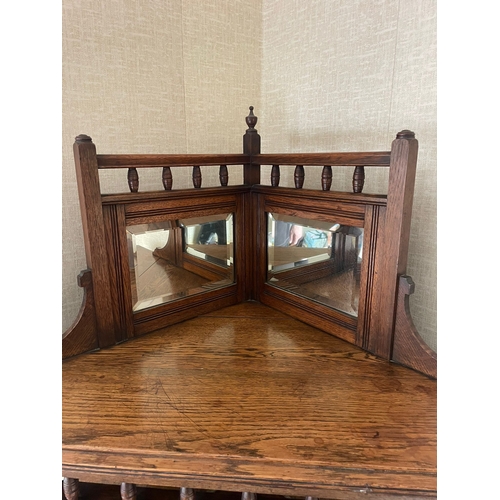 318 - AN OAK MIRROR BACKED CORNER CABINET, to the top is a raised gallery back with turned columns & a fin... 