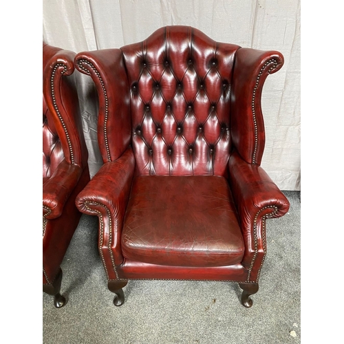 15 - A GOOD PAIR OF OXBLOOD LEATHER WINGBACK CHESTERFIELD ARMCHAIRS, the arched button back upholstered b... 