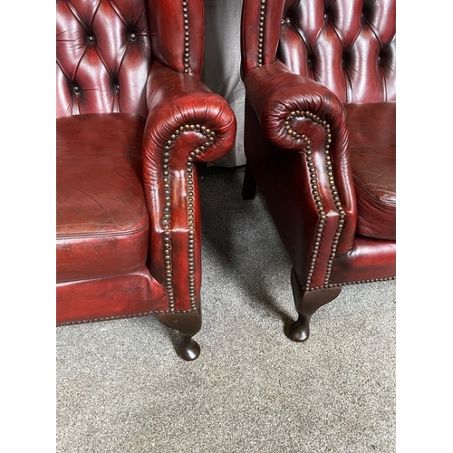 15 - A GOOD PAIR OF OXBLOOD LEATHER WINGBACK CHESTERFIELD ARMCHAIRS, the arched button back upholstered b... 