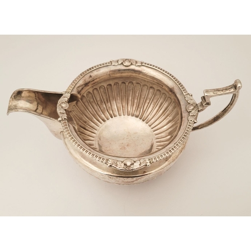 19 - AN IRISH EARLY 19TH GEORGE III SILVER CREAM JUG, with gadrooned rim having floral points, the body f... 