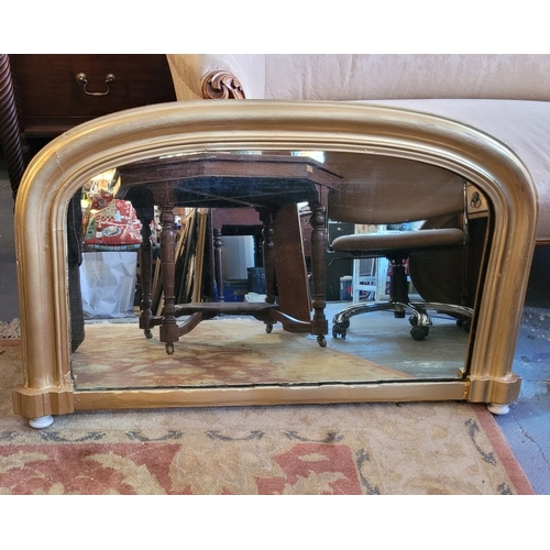 104 - A CURVED GILTWOOD OVERMANTLE WITH CERAMIC FENIALS TO THE LOWER CORNERS, panelled back, in very good ... 