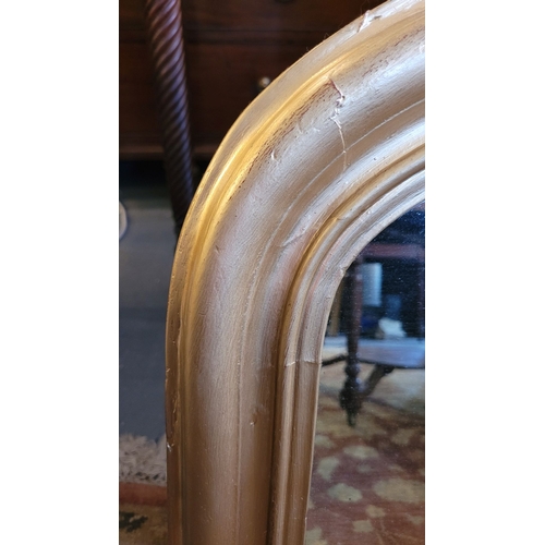 104 - A CURVED GILTWOOD OVERMANTLE WITH CERAMIC FENIALS TO THE LOWER CORNERS, panelled back, in very good ... 