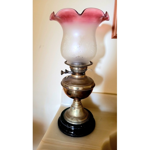 121 - A VICTORIAN CRANBERRY & BRASS OIL LAMP, with a ruffle shaped cranberry & clear glass shade with acid... 