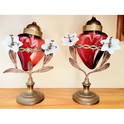 126 - AN UNUSUALLY PAIR OF SACRED HEART VOTIVE LAMPS, each with a cranberry red glass heart that rests wit... 