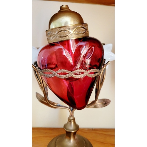 126 - AN UNUSUALLY PAIR OF SACRED HEART VOTIVE LAMPS, each with a cranberry red glass heart that rests wit... 