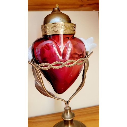 126 - AN UNUSUALLY PAIR OF SACRED HEART VOTIVE LAMPS, each with a cranberry red glass heart that rests wit... 