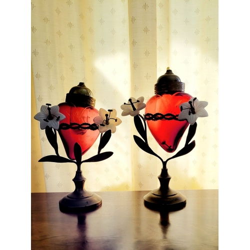 126 - AN UNUSUALLY PAIR OF SACRED HEART VOTIVE LAMPS, each with a cranberry red glass heart that rests wit... 