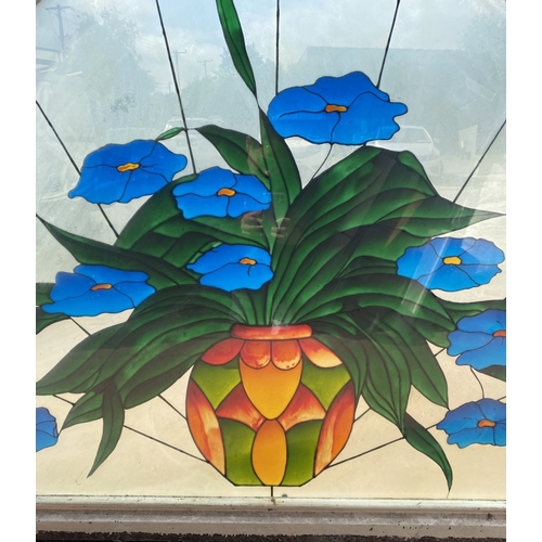 130 - A BEAUTIFUL ARCHED STAINED GLASS WINDOW, c.1993, with blue flowers in vase in vibrant colours, signe... 