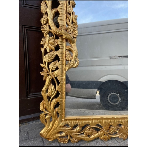 30 - AN EXCEPTIONAL HIGHLY CARVED GILTWOOD OVERMANTLE/HALL MIRROR, with rectangular mirror in extensively... 