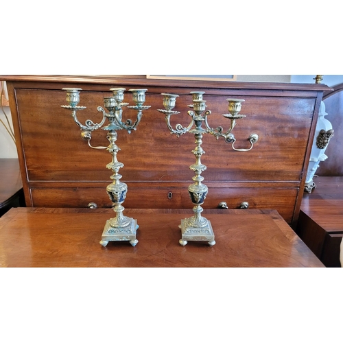 79 - A PAIR OF DECORATIVE BRASS GARNITURES – FOUR HEAD CANDELABRA, each with three outer candle holders a... 