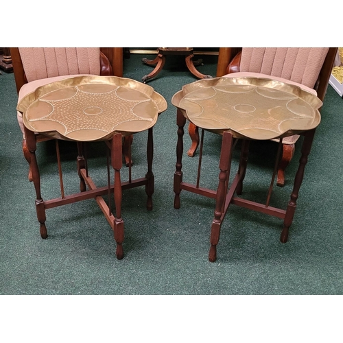 69 - A PAIR OF COLLAPSABLE BRASS TRAY TOP TABLES, each of the tables has a scalloped brass hand beaten tr... 