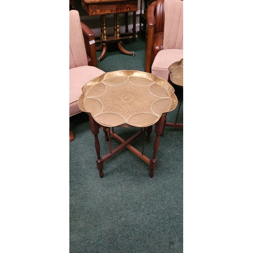 69 - A PAIR OF COLLAPSABLE BRASS TRAY TOP TABLES, each of the tables has a scalloped brass hand beaten tr... 