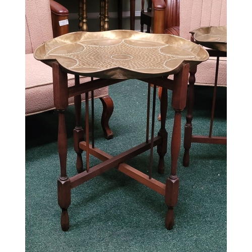 69 - A PAIR OF COLLAPSABLE BRASS TRAY TOP TABLES, each of the tables has a scalloped brass hand beaten tr... 