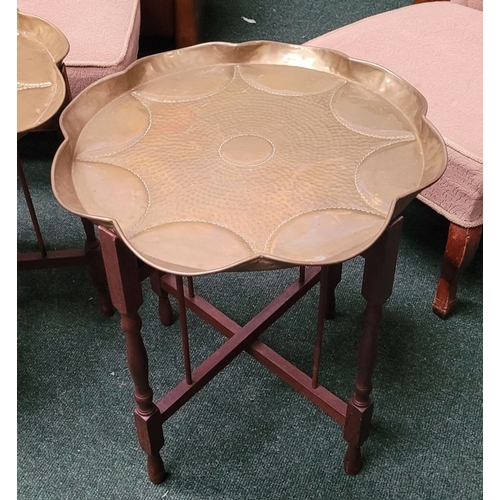 69 - A PAIR OF COLLAPSABLE BRASS TRAY TOP TABLES, each of the tables has a scalloped brass hand beaten tr... 