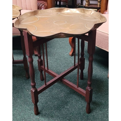 69 - A PAIR OF COLLAPSABLE BRASS TRAY TOP TABLES, each of the tables has a scalloped brass hand beaten tr... 