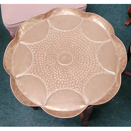 69 - A PAIR OF COLLAPSABLE BRASS TRAY TOP TABLES, each of the tables has a scalloped brass hand beaten tr... 