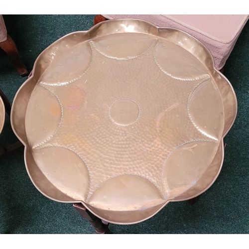 69 - A PAIR OF COLLAPSABLE BRASS TRAY TOP TABLES, each of the tables has a scalloped brass hand beaten tr... 