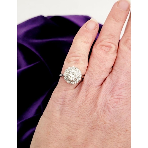 101 - A VERY FINE 18CT WHITE GOLD DIAMOND CLUSTER RING, with a large raised central round diamond, surroun... 