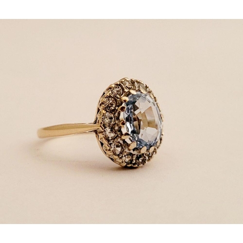 109 - A PRETTY 9CT YELLOW GOLD AQUAMARINE CLUSTER RING, the central oval shaped pale blue stone sits insid... 