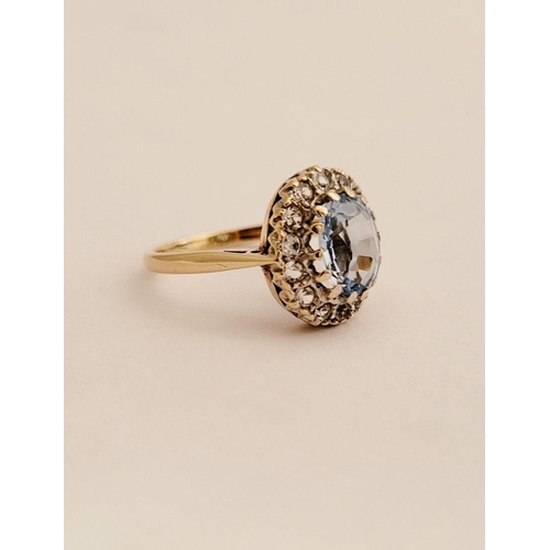 109 - A PRETTY 9CT YELLOW GOLD AQUAMARINE CLUSTER RING, the central oval shaped pale blue stone sits insid... 