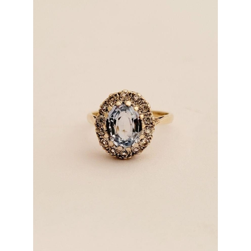 109 - A PRETTY 9CT YELLOW GOLD AQUAMARINE CLUSTER RING, the central oval shaped pale blue stone sits insid... 