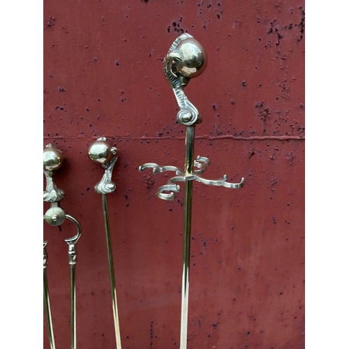 112 - A GOOD SET OF FOUR POLISHED BRASS FIRE IRONS ON STAND, to include shovel, brush, tongs and poker, al... 