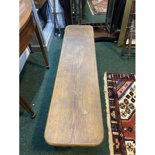 156 - A LONG HARDWOOD BENCH, the rectangular top with canted corners, with shaped supports joining a doubl... 