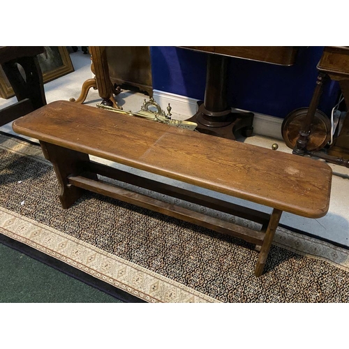 179 - A LONG HARDWOOD BENCH, the rectangular top with canted corners, with shaped supports joining a doubl... 