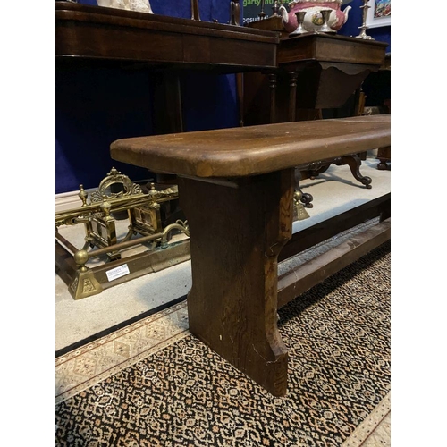 179 - A LONG HARDWOOD BENCH, the rectangular top with canted corners, with shaped supports joining a doubl... 