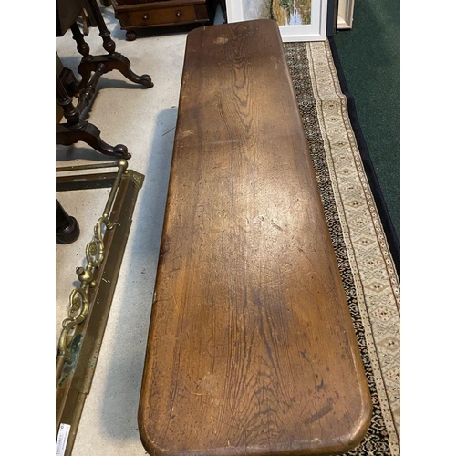 179 - A LONG HARDWOOD BENCH, the rectangular top with canted corners, with shaped supports joining a doubl... 