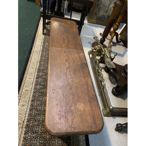 179 - A LONG HARDWOOD BENCH, the rectangular top with canted corners, with shaped supports joining a doubl... 