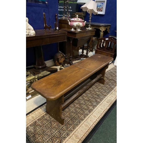 179 - A LONG HARDWOOD BENCH, the rectangular top with canted corners, with shaped supports joining a doubl... 