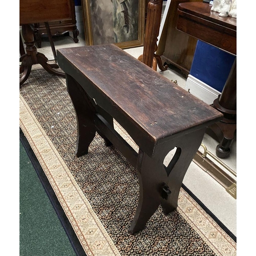 181 - A DARK STAINED HARDWOOD STOOL/BENCH, with shaped supports joined by a cross stretcher. The supports ... 