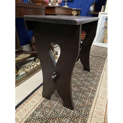 181 - A DARK STAINED HARDWOOD STOOL/BENCH, with shaped supports joined by a cross stretcher. The supports ... 