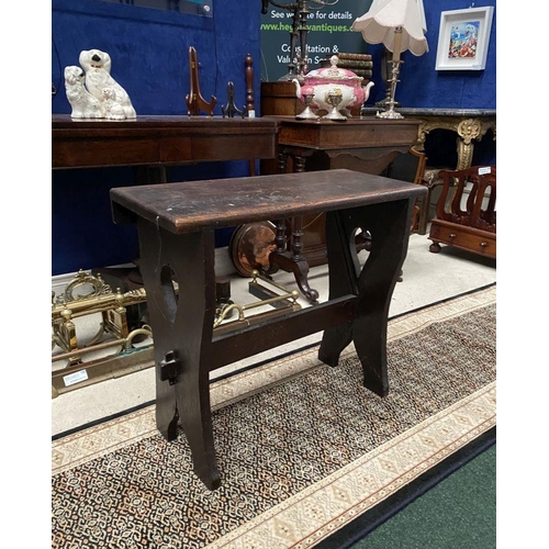 181 - A DARK STAINED HARDWOOD STOOL/BENCH, with shaped supports joined by a cross stretcher. The supports ... 