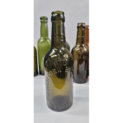 199 - A GREAT COLLECTION OF VINTAGE COLOURED GLASS BOTTLES, includes 5 West Cork Bottling bottles, a Cade’... 