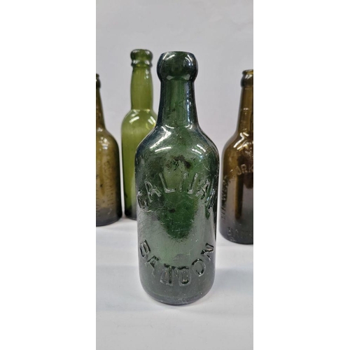 199 - A GREAT COLLECTION OF VINTAGE COLOURED GLASS BOTTLES, includes 5 West Cork Bottling bottles, a Cade’... 