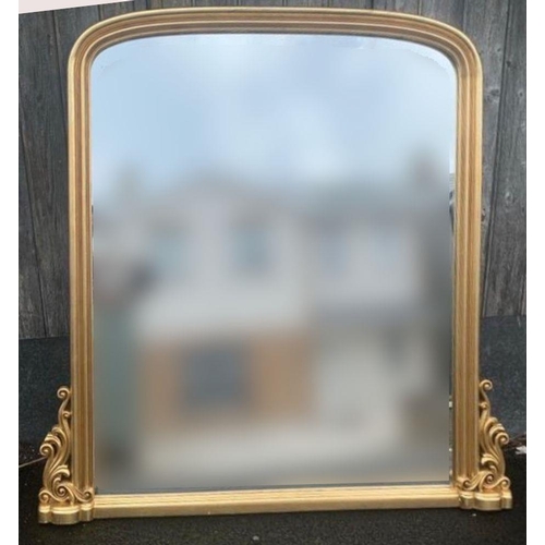 249 - AN ARCHED GILT WALL MIRROR / OVER MANTLE MIRROR, with scrolling upright detail to the lower corners.... 